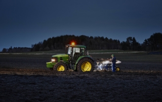 Flashlight_field_with_tractor Professional farmer inspecting his John Deere tractor with the powerful Suprabeam Q7compact flashlight